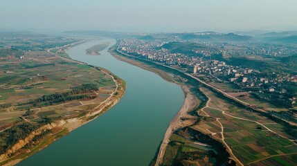 Obraz premium Aerial View of a Serene River Meandering Through Lush Farmlands and a Small Town