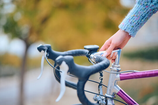 Person adjusting bicycle handlebar on a sunny autumn day in a park