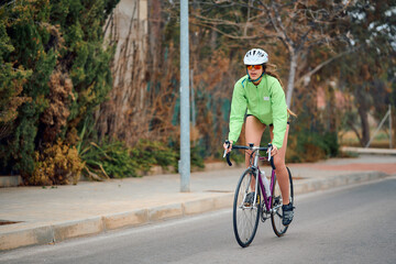 Cyclist riding on a quiet street in bright green jacket during daytime