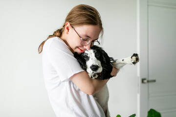 Blonde-haired girl distracted from her tasks, kissing the Spaniel puppy she is holding in her arms