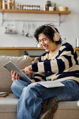 Fototapeta premium Joyful student engages in online studies at home while enjoying his favorite tunes