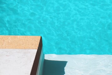 Cool turquoise water ripples gently near a sunlit poolside in a tranquil setting