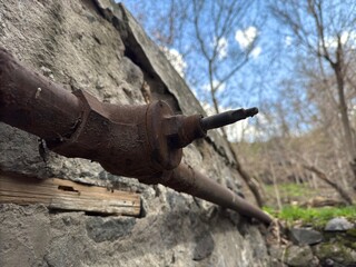Rusty pipe along grey concrete wall against blue sky