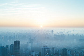 Fototapeta premium Aerial view of cityscape covered in smog and pollution during sunrise, creating hazy atmosphere
