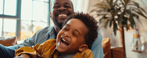 Father and son are sharing a happy moment together, laughing out loud in their living room
