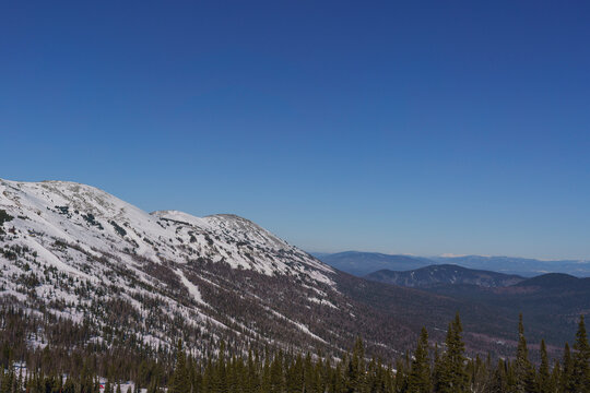 panorama of the winter Altai mountain landscape, mountain peaks in a misty haze, mountain slopes covered with snow