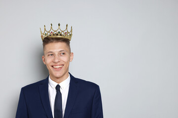 Handsome man wearing luxury crown on gray background, space for text