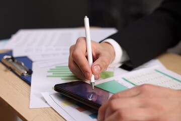 Electronic signature. Man using stylus and smartphone at wooden table, closeup