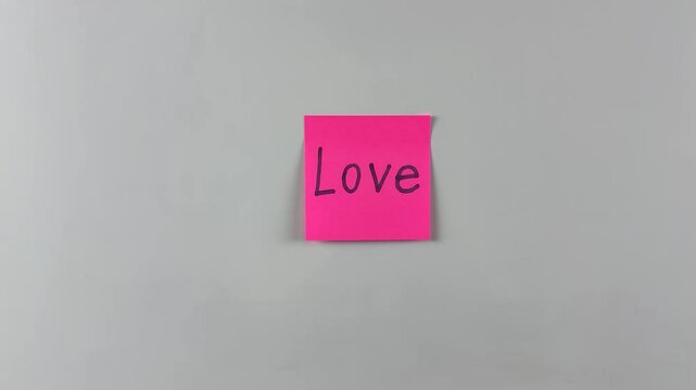 Sticky note with word Love written on it, affixed to white background. Perfect for themes of affection, connection, and care. Great for emotional and relationship visuals