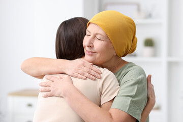 Woman with cancer and her daughter hugging at home