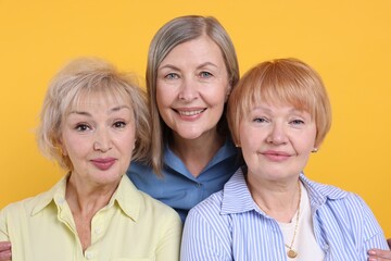 Friendship. Portrait of senior women on orange background