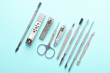 Set of different manicure tools on turquoise background, flat lay