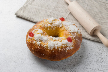 Delicious roscón de reyes cake sprinkled with sugar and candied fruit, near a rolling pin