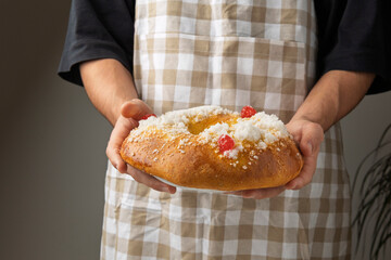 Pastry chef holding roscón de reyes, spanish traditional cake for epiphany, decorated with candied...