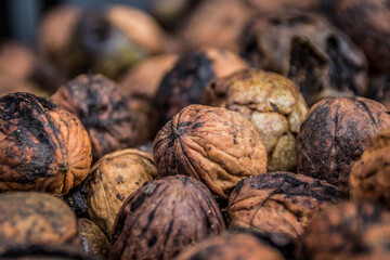 A close-up of a large pile of walnuts in their shells, highlighting their rough texture and natural brown tones. Rustic and organic, perfect for food and agriculture themes.