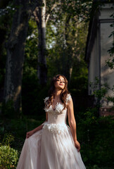 Fototapeta premium Stunning bride gracefully poses in a spring park, among blossoming trees. exuding elegance,