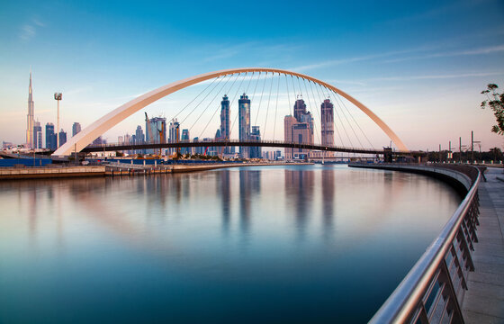 Colorful sunset over Dubai Downtown skyscrapers and newly built Tolerance bridge viewed from Dubai water canal, Dubai, United Arab Emirates