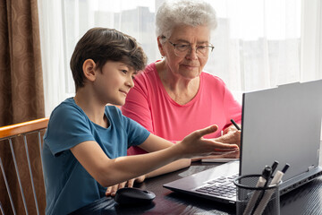 Young boy teaching his grandmother computer skills – digital literacy across generations....