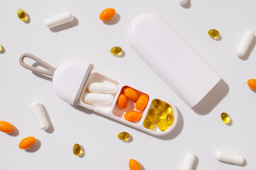 Stylish pillbox, organizer for vitamins, capsules, dietary supplements, tablets on light gray background. Solar lighting. Multivitamins, health support, homeopathy. Minimalistic concept Solar lighting