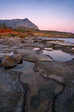 Aspes beach, natural holes in the rocks full of water at sunset, with sea in the background