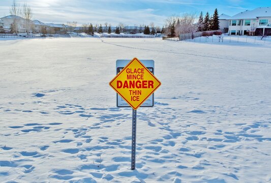 Sign warning of thin ice on a frozen lake in Linden Ridge, Winnipeg, Manitoba, Canada