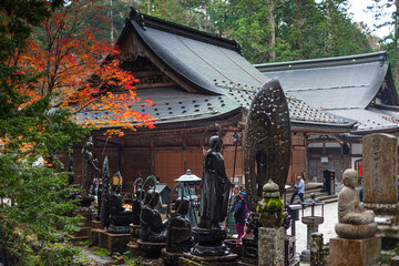 A traditional Japanese temple surrounded by gravestones and vibrant autumn foliage in sacred grounds of Koyasan (Mount Koya), Honshu