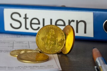 Symbolische Bitcoins vor einem Ordner mit der Aufschrift STEUER © U. J. Alexander