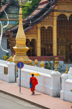 Novice monk walking in Sakkarine Rd in front of Wat Sop temple, Luang Prabang, northern Laos