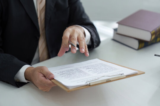 Legal Documentation and Procedural Discussion. A lawyer reviewing case files with clients in an office setting.