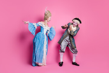 Elegant couple in historic costumes poses against a vibrant pink backdrop, showcasing playful expressions and classic attire