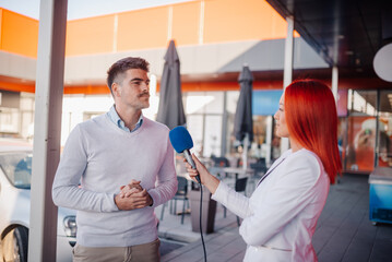 Journalist interviewing businessman holding microphone outdoors