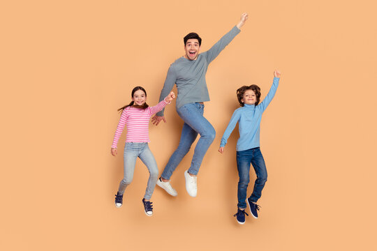 Happy family of three joyfully jumping against a beige background symbolizing happiness, togetherness, and love