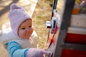 Child Enjoying a Colorful Gumball Machine Near a Park on a Sunny Day in Early Spring