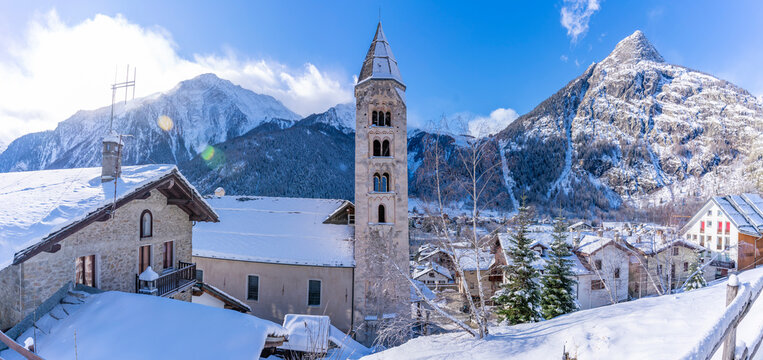 View of snow covered mountains, rooftops and Church of Saint Pantalon in Courmayeur in winter, Courmayeur, Aosta Valley, Italian Alps