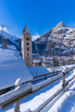 View of snow covered mountains, rooftops and Church of Saint Pantalon in Courmayeur in winter, Courmayeur, Aosta Valley, Italian Alps