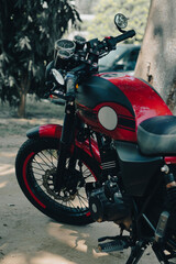 A stylish red and black retro motorcycle with a sleek fuel tank and classic gauges, parked on a...