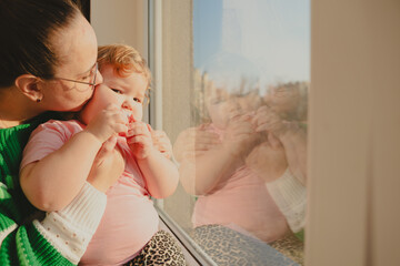 Child Enjoys a Moment by the Window With an Adult in Soft Evening Light