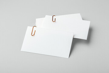 Blank white business card with copper gold clip mockup on light grey background