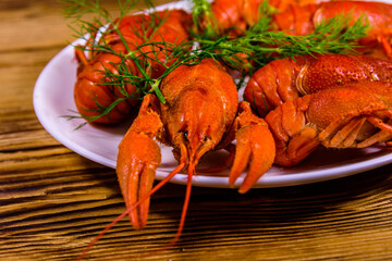 Plate with boiled crayfishes on wooden table