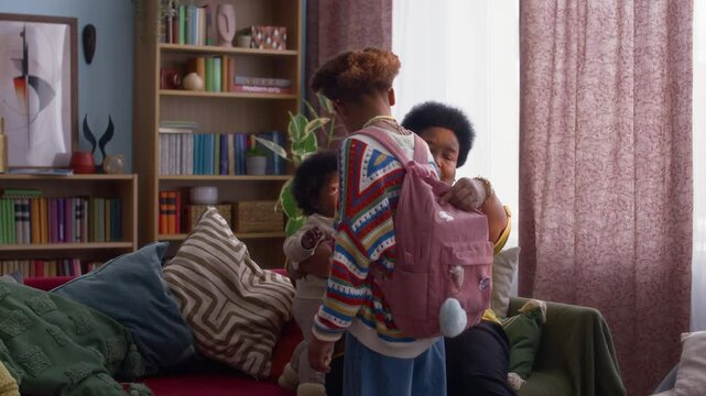 Loving African American grandmother looking arter two of her grandchildren in colorful living room