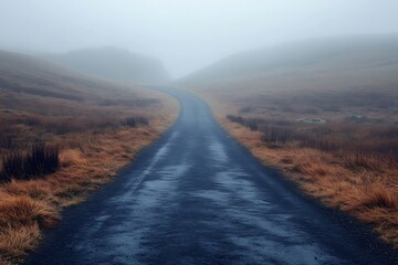 A road disappearing into the rolling fog of a moor, with only the faint outlines of distant hills and boggy terrain visible