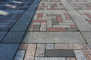 Texture of square paving tile. Pattern of gray, red, orange and beige sidewalk tiles in the street. Concrete pavers close up background.