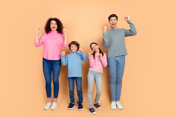 Naklejka premium Joyful family of four celebrating on beige backdrop, showcasing happiness, togetherness