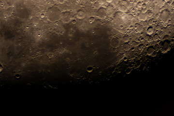 Lunar surface filled with craters and shadows in golden hue