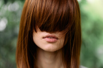 Vulnerable woman with long red hair covering her face in distress with eyes closed