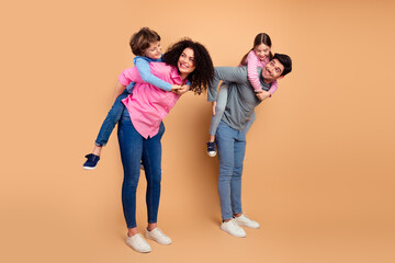 Fototapeta premium Happy family having fun together while enjoying leisure time with children in a warm and casual setting against a beige background.