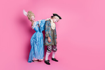 Elegant couple in baroque costumes poses against a vibrant pink backdrop, showcasing whimsical...