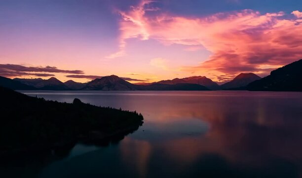 The sun is setting over the water with mountains in the background