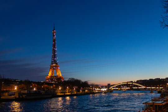 Paris, France - February 24, 2025: night view of the illuminated Eiffel Tower and Pont Debilly Footbridge on river Seine in Paris, France
