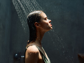 Refreshing moment of a woman standing under a shower head with water flowing over her head